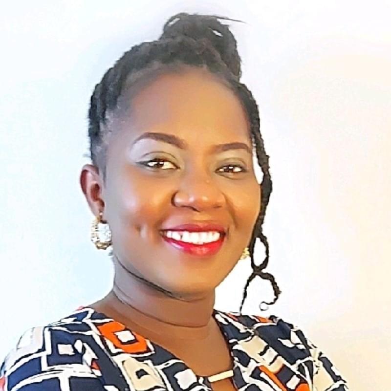Headshot of a smiling Black woman wearing red lipstick, small hoop earrings and braids in an up-do.